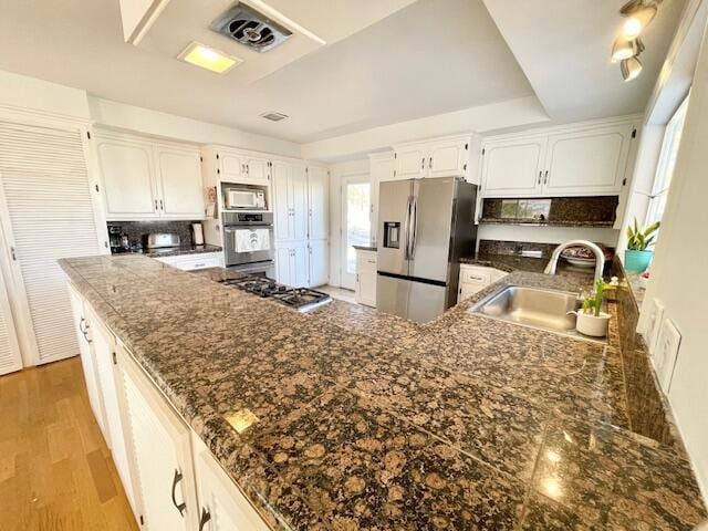 kitchen featuring tasteful backsplash, light hardwood / wood-style floors, sink, white cabinetry, and appliances with stainless steel finishes