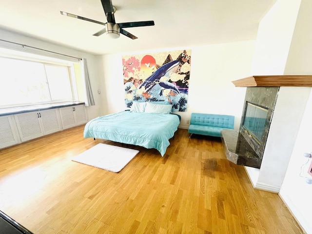 bedroom featuring ceiling fan, a fireplace, and hardwood / wood-style flooring