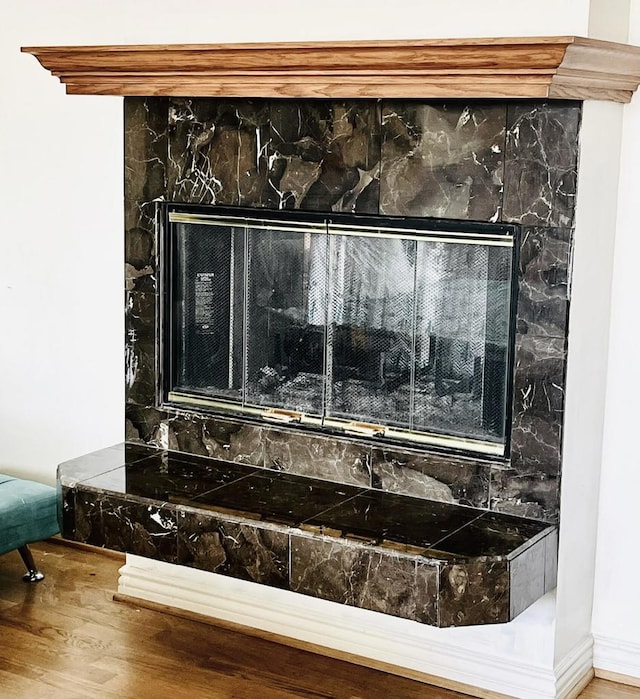 interior details with wood-type flooring and a tile fireplace