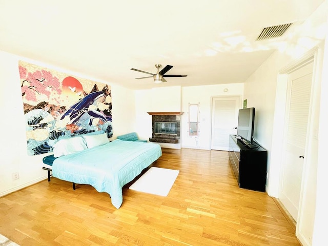 bedroom with ceiling fan, a closet, wood-type flooring, and a multi sided fireplace