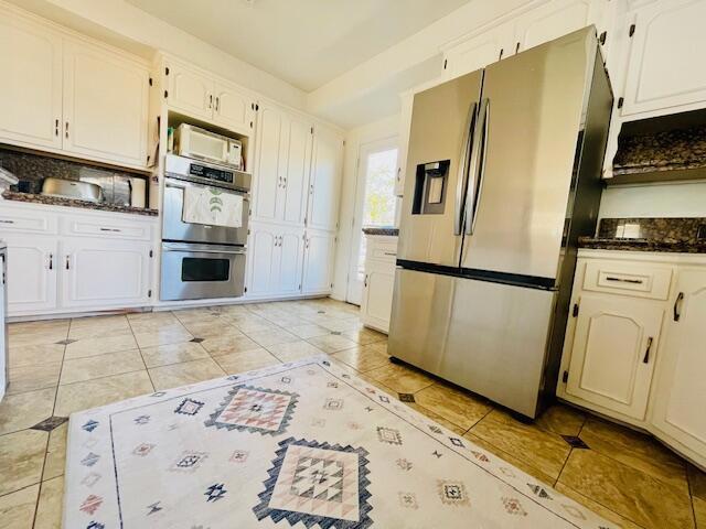 kitchen with light tile patterned flooring, stainless steel appliances, and white cabinets