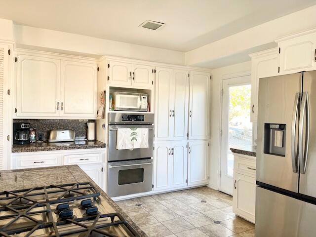 kitchen featuring white cabinets, decorative backsplash, and appliances with stainless steel finishes