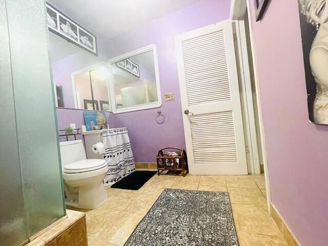 bathroom with toilet, tile patterned flooring, and a shower