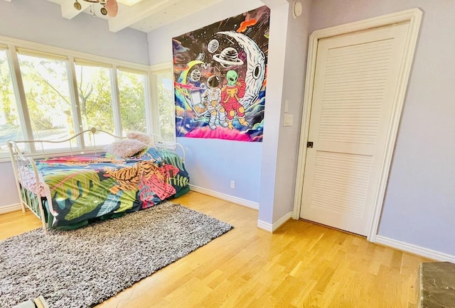 bedroom with a closet, beamed ceiling, and hardwood / wood-style flooring