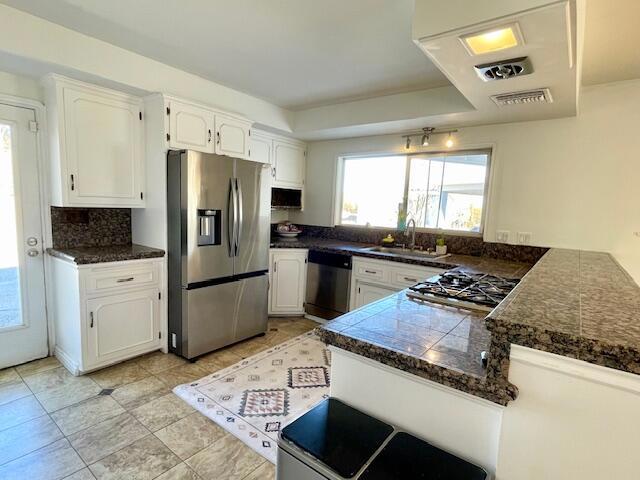 kitchen featuring white cabinetry, stainless steel appliances, sink, backsplash, and kitchen peninsula