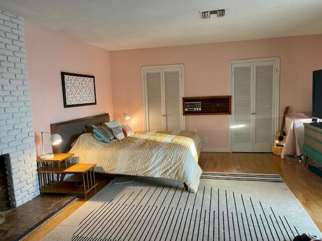 bedroom with a brick fireplace and hardwood / wood-style flooring