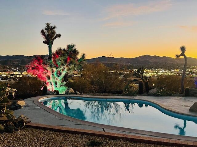 pool at dusk with a mountain view and a patio area