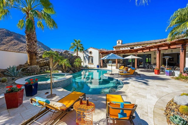 view of pool featuring a patio area, a mountain view, and an in ground hot tub