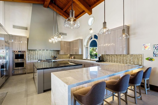 kitchen with decorative light fixtures, stainless steel double oven, and beamed ceiling