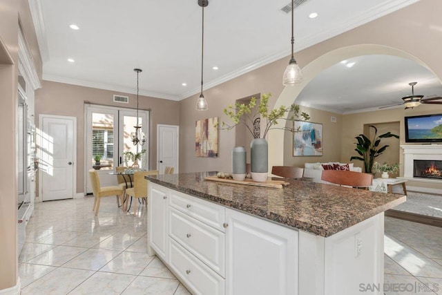 kitchen with white cabinetry, ceiling fan, hanging light fixtures, crown molding, and dark stone counters