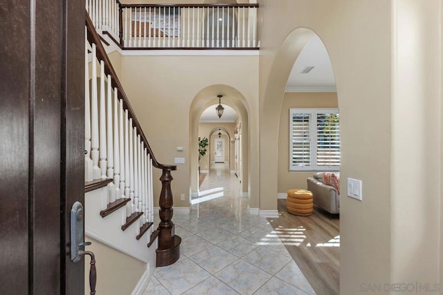 entrance foyer with ornamental molding and a towering ceiling