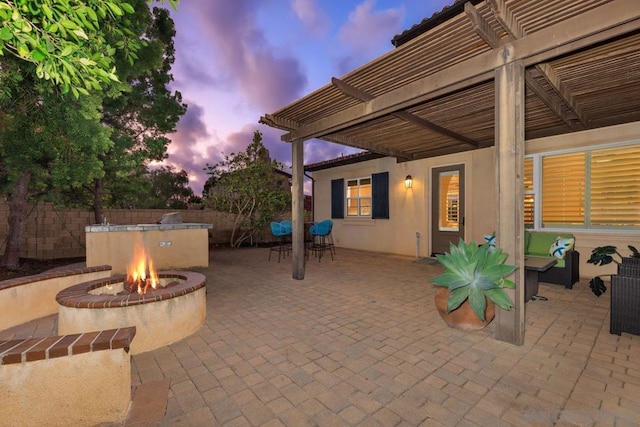 patio terrace at dusk featuring a pergola and an outdoor fire pit