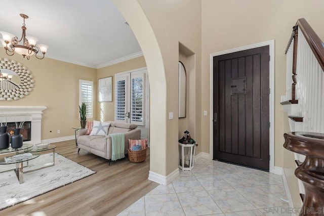 entryway with an inviting chandelier, light wood-type flooring, and ornamental molding