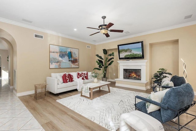 living room with ceiling fan, light wood-type flooring, and crown molding