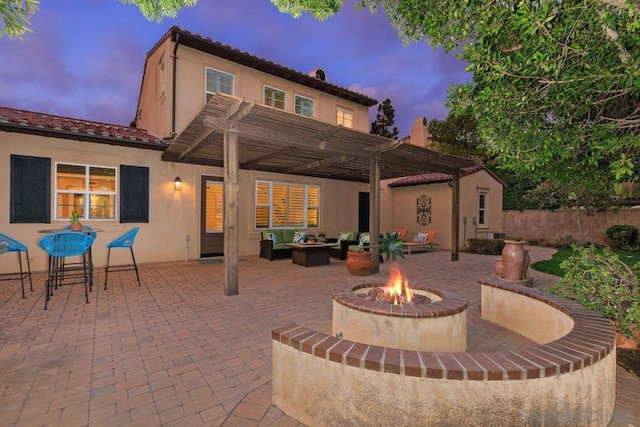 patio terrace at dusk with a pergola and an outdoor living space with a fire pit