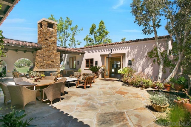 back of house with an outdoor living space with a fireplace and a patio