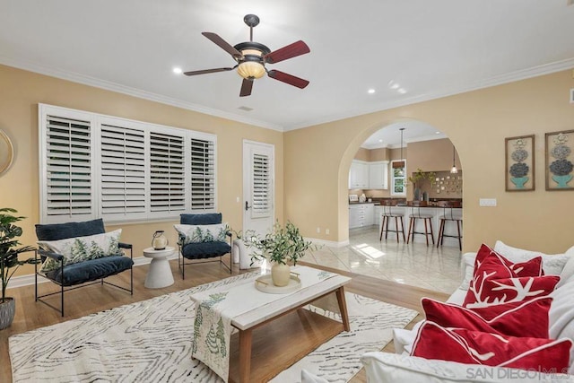 living room with light hardwood / wood-style floors, ceiling fan, and crown molding