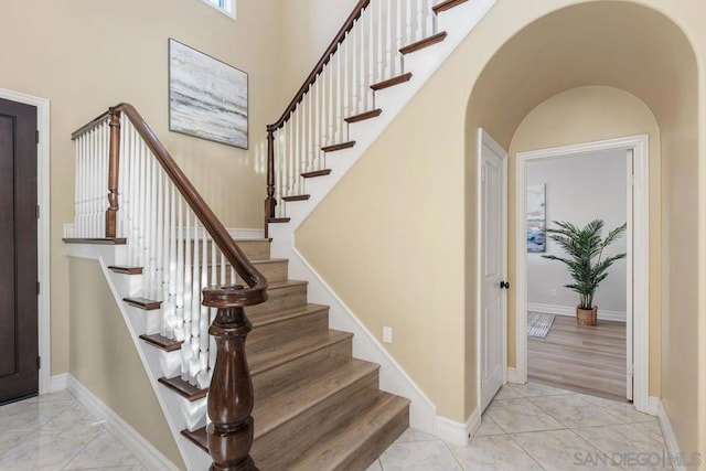 stairs featuring a towering ceiling and wood-type flooring