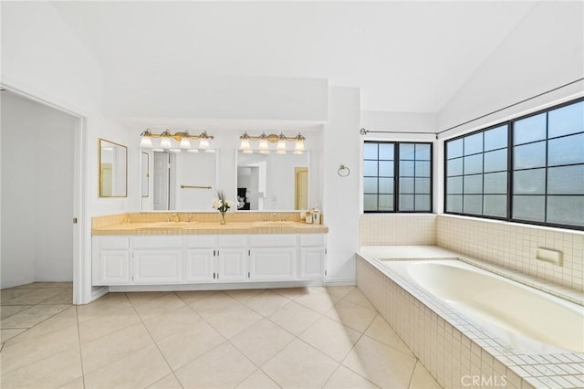 bathroom featuring tile patterned flooring, vanity, a relaxing tiled tub, and vaulted ceiling