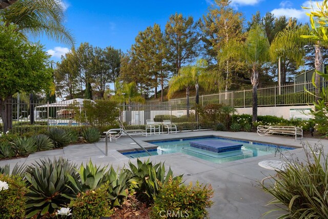 view of swimming pool featuring a patio and a hot tub