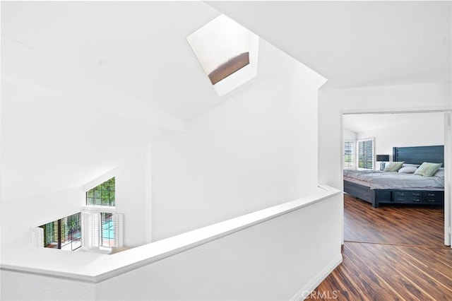 hall featuring dark hardwood / wood-style floors, vaulted ceiling, and a wealth of natural light