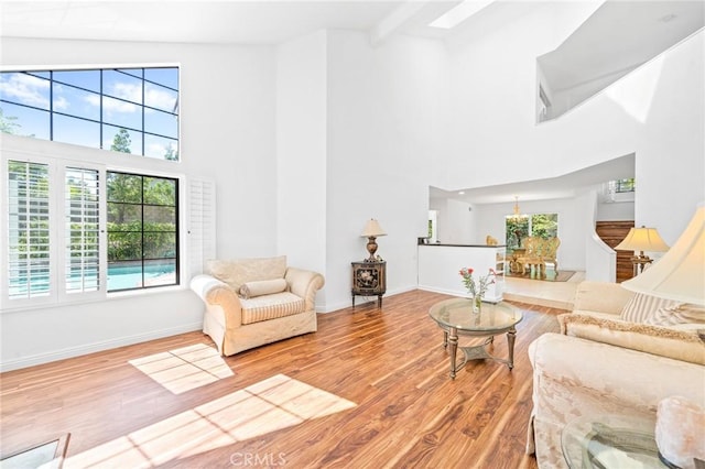 living room with beam ceiling, light hardwood / wood-style flooring, and high vaulted ceiling