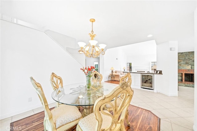 tiled dining room featuring a stone fireplace, a chandelier, and beverage cooler