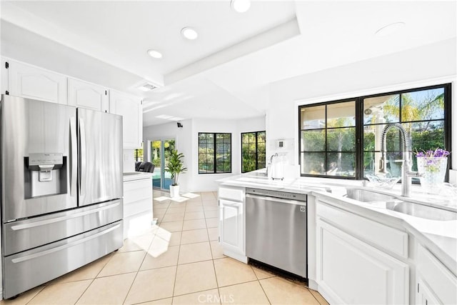 kitchen with light tile patterned floors, stainless steel appliances, a sink, white cabinets, and light countertops