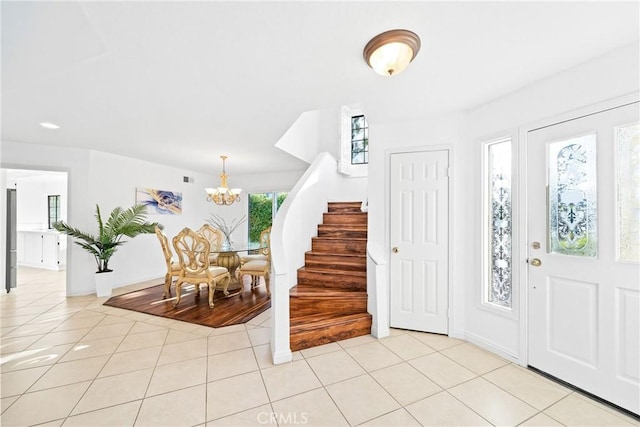 foyer featuring light tile patterned floors, stairway, and an inviting chandelier