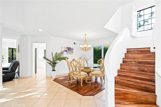 dining space with a healthy amount of sunlight, a notable chandelier, stairway, and light tile patterned floors