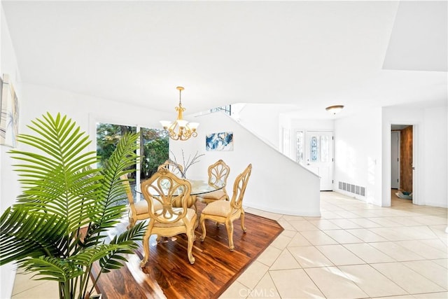 dining area with light tile patterned floors, baseboards, visible vents, and a chandelier