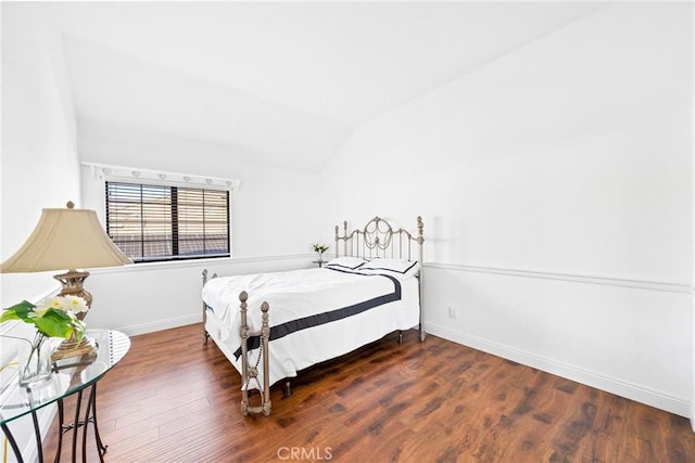 bedroom with baseboards, vaulted ceiling, and wood finished floors