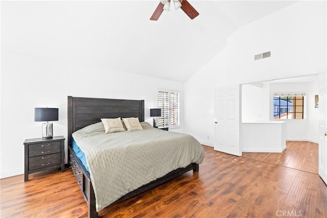 bedroom with high vaulted ceiling, baseboards, visible vents, and wood finished floors