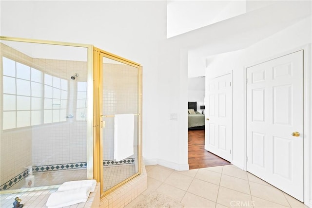 ensuite bathroom with a stall shower, connected bathroom, baseboards, and tile patterned floors