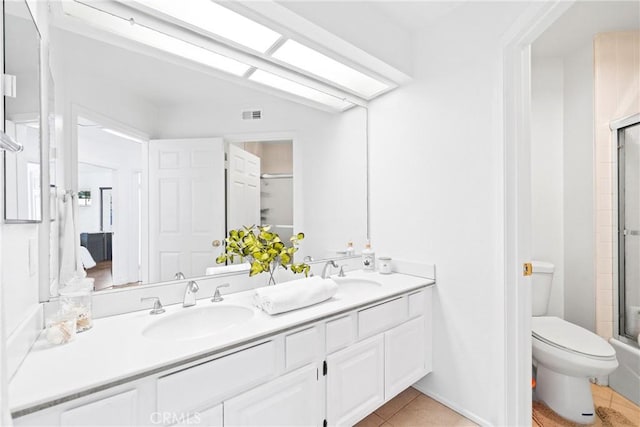 full bathroom with a shower with shower door, a sink, toilet, and double vanity