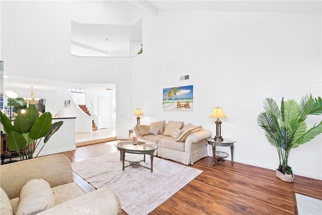 living area featuring visible vents, wood finished floors, high vaulted ceiling, baseboards, and stairs