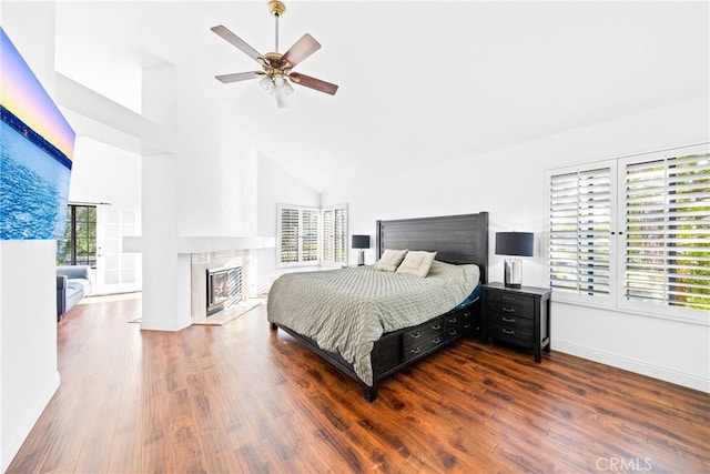 bedroom with baseboards, high vaulted ceiling, wood finished floors, and a tile fireplace