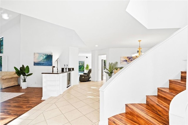 entrance foyer featuring lofted ceiling, an inviting chandelier, stairway, and light tile patterned flooring