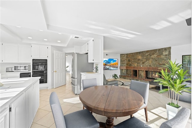 dining area featuring light tile patterned floors, recessed lighting, visible vents, and a stone fireplace