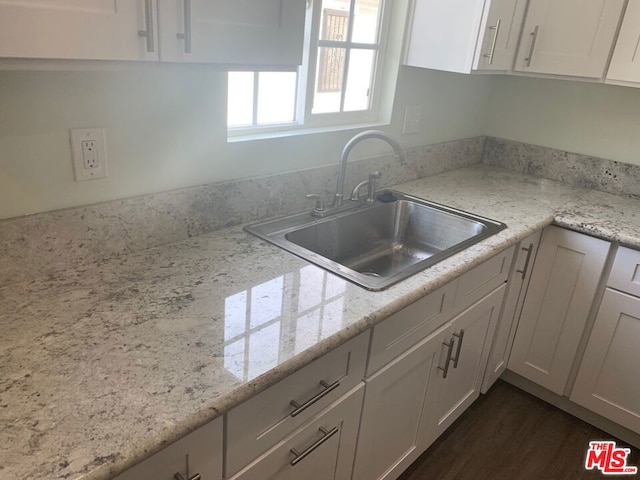 kitchen featuring light stone countertops, dark hardwood / wood-style floors, white cabinetry, and sink