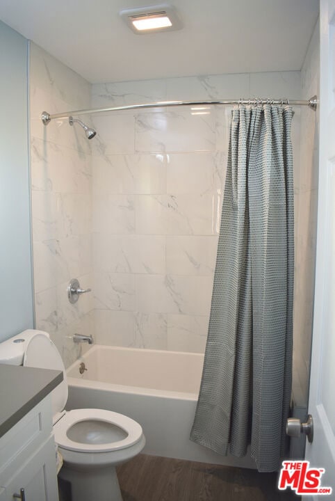 full bathroom featuring hardwood / wood-style floors, vanity, toilet, and shower / bath combo