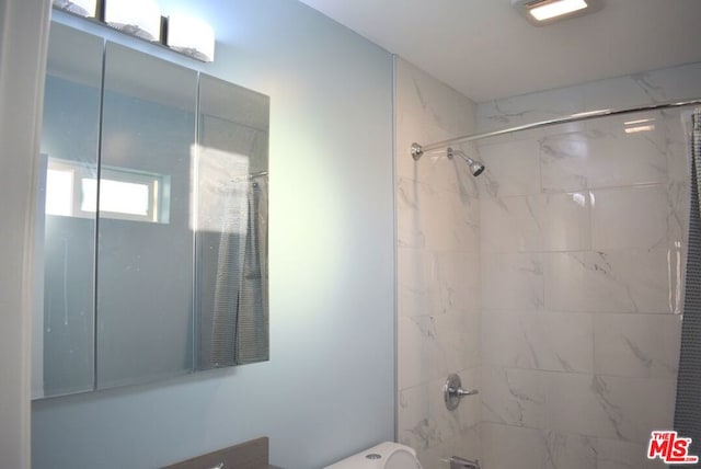 bathroom featuring tiled shower / bath combo and toilet