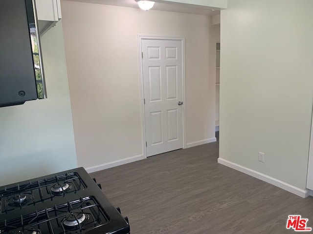 interior space with dark hardwood / wood-style floors, black stove, and white cabinetry