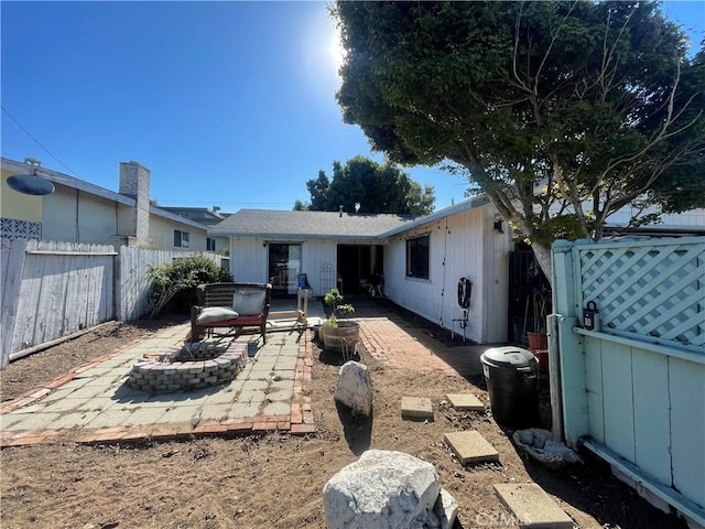 back of property with a fire pit and a patio area