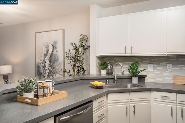 kitchen featuring stainless steel dishwasher, backsplash, white cabinetry, and sink