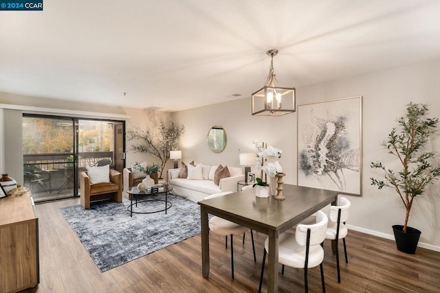 dining space featuring wood-type flooring and a notable chandelier