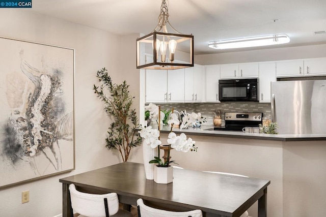 kitchen with tasteful backsplash, a breakfast bar, stainless steel appliances, white cabinets, and hanging light fixtures