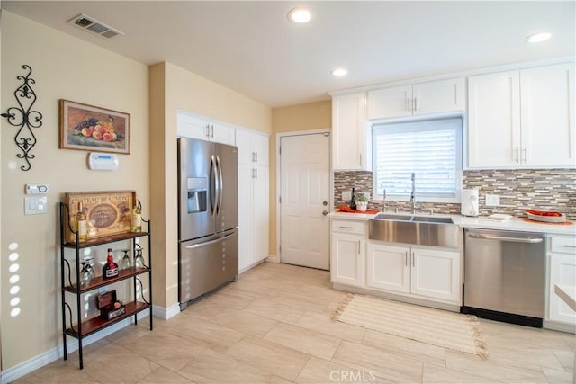 kitchen featuring backsplash, white cabinetry, sink, and appliances with stainless steel finishes