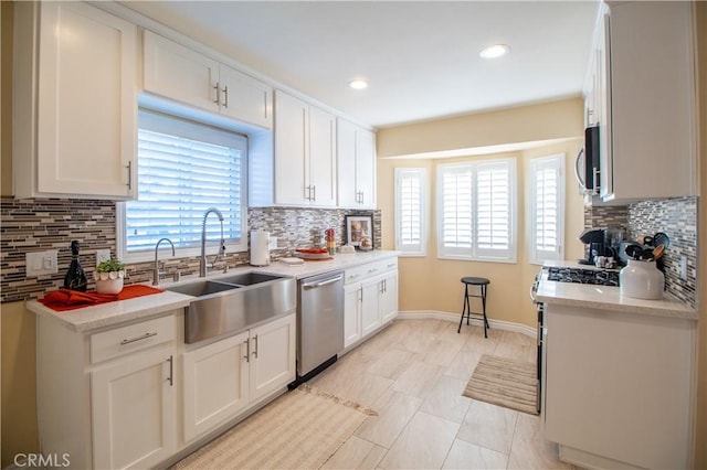 kitchen with white cabinets, decorative backsplash, sink, and appliances with stainless steel finishes