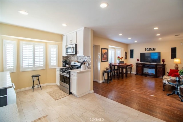 kitchen with decorative backsplash, white cabinetry, and appliances with stainless steel finishes